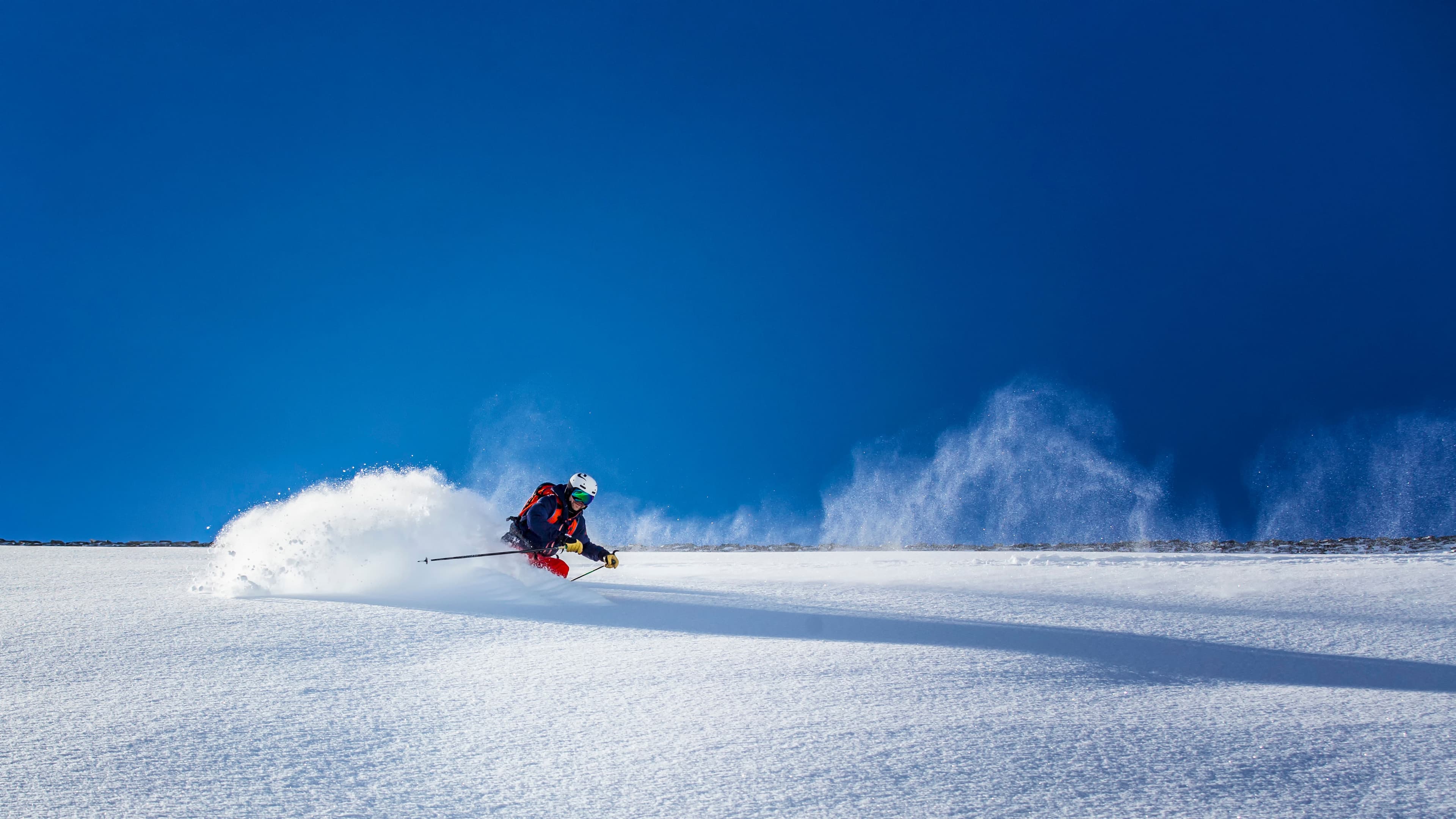Backcountry skiier skiing powder on a bluebird day